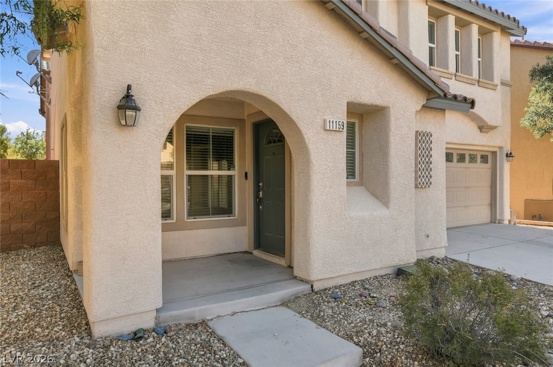11159 Ranch Valley Street Las Vegas, NV 89179 - Photo 3 of 27 An inviting arched entryway welcomes you to this stucco residence, featuring an attached garage and low-maintenance landscaping.