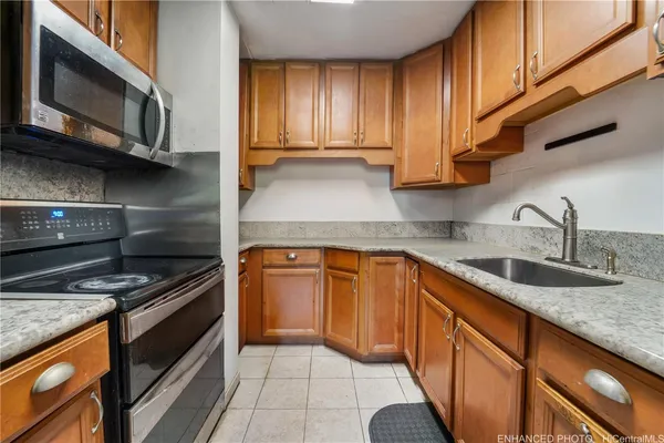 a kitchen with kitchen island granite countertop a sink stainless steel appliances wooden cabinets and a counter top space
