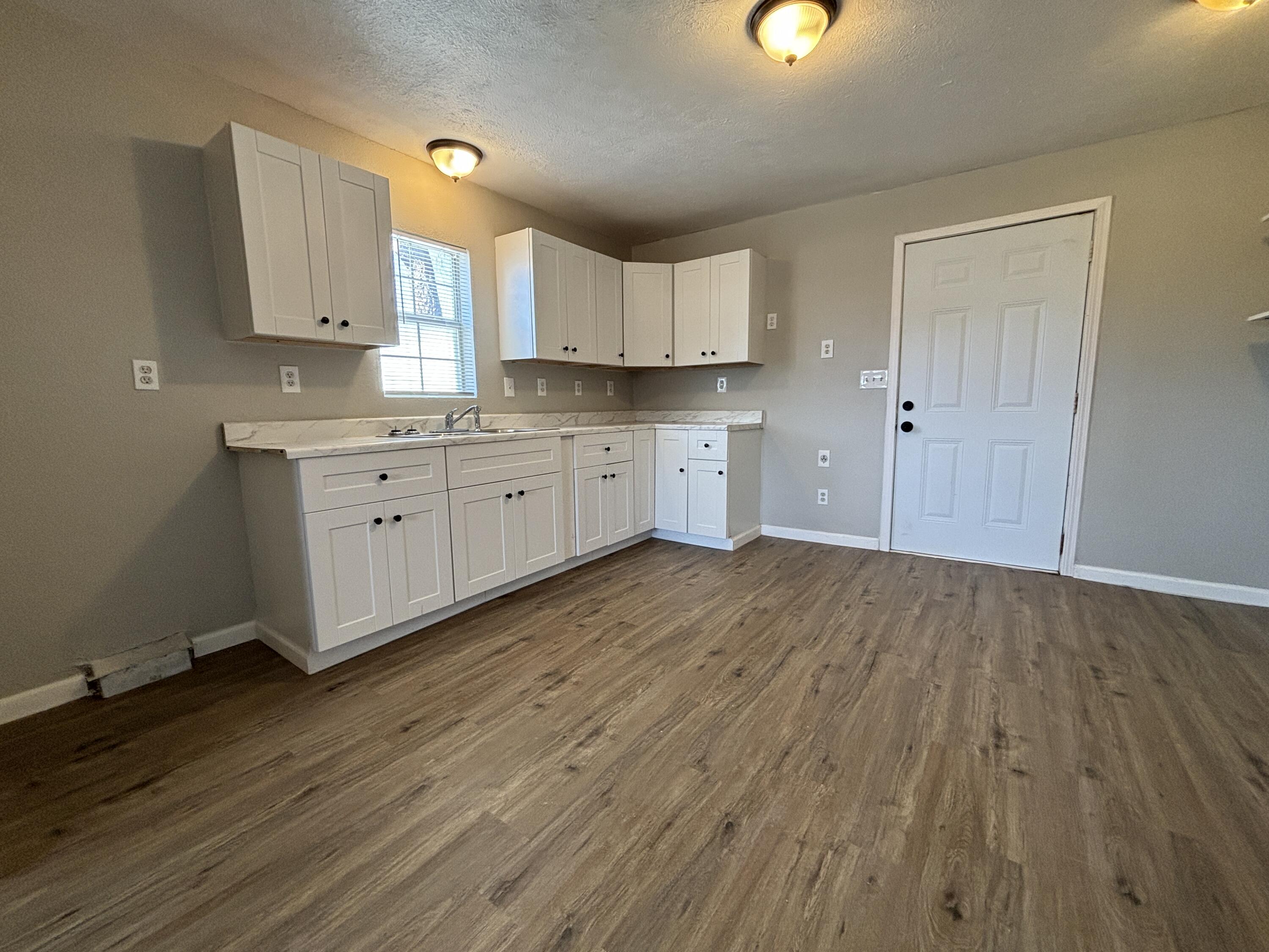 4822 37th Street Lubbock, TX 79414 - Photo 4 of 12 a room with kitchen island white cabinets and wooden floor
