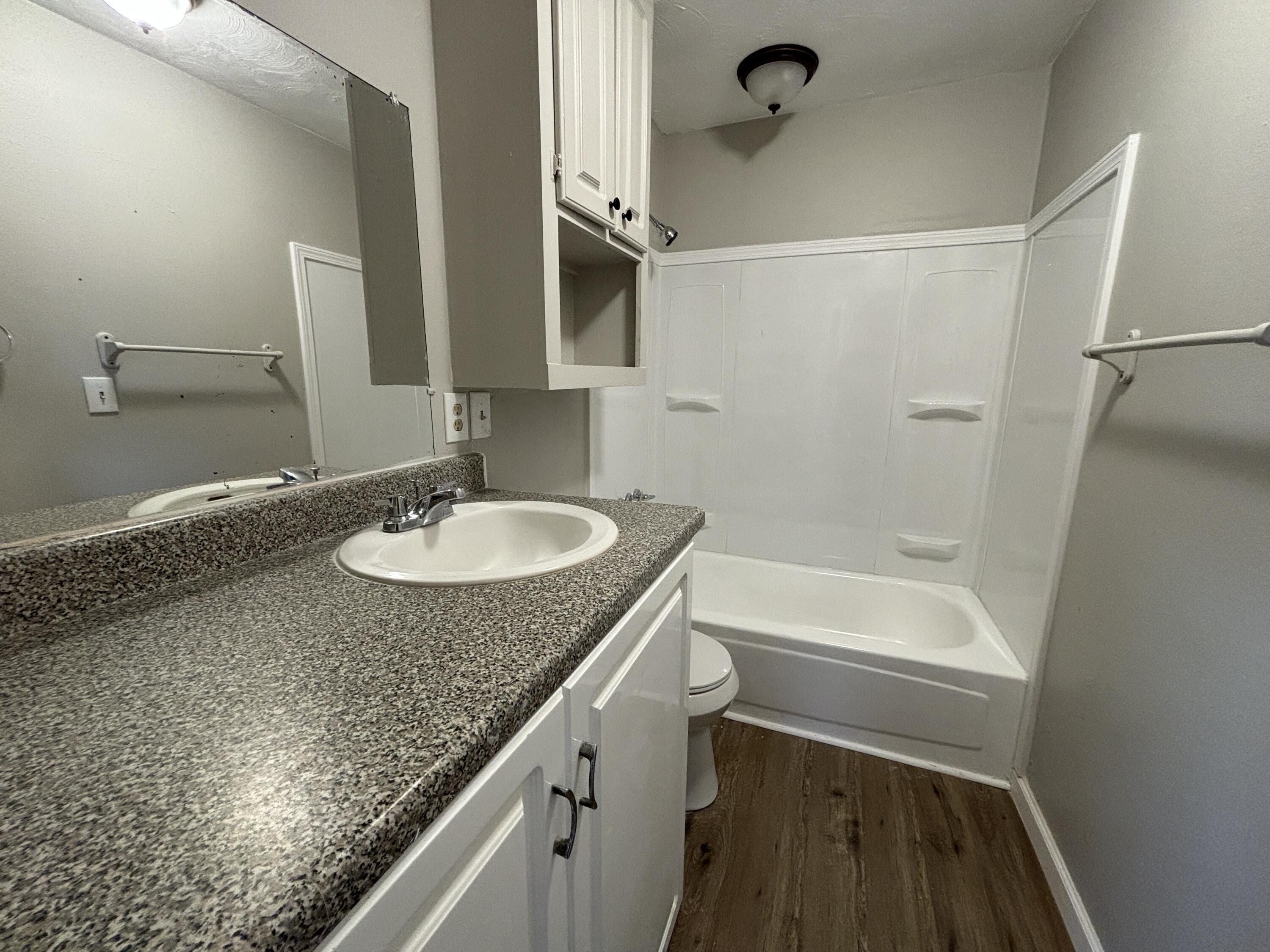4822 37th Street Lubbock, TX 79414 - Photo 10 of 12 a bathroom with a granite countertop sink a mirror and a bathtub