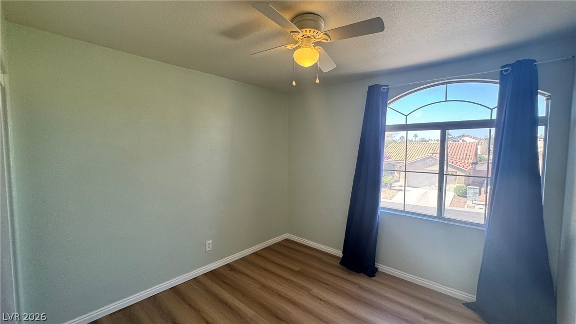 9716 Ridge Creek Place Las Vegas, NV 89134 - Photo 15 of 28 This bright bedroom features a large arched window with a street view and durable wood flooring.