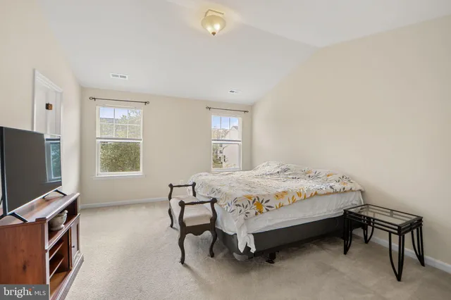 a bedroom with a bed and a flat tv screen on a dresser