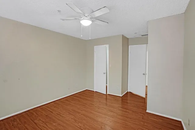 an empty room with wooden floor and ceiling fan