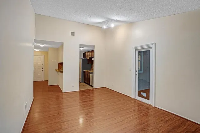 a view of an empty room with wooden floor and closet