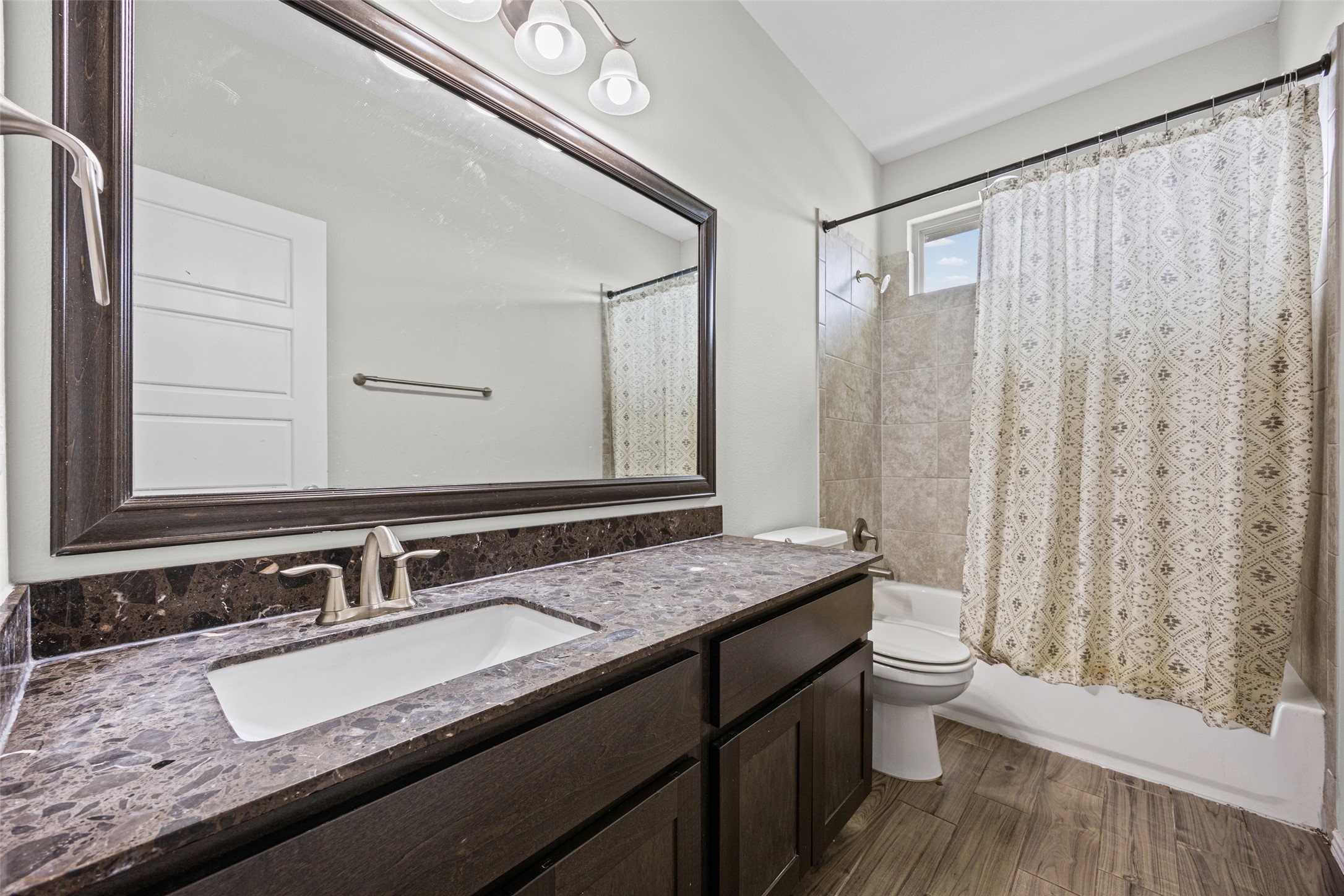 17401 Silent Harbor Loop Pflugerville, TX 78660 - Photo 33 of 37 Bathroom featuring shower / bath combo with shower curtain, vanity, and dark wood finished floors