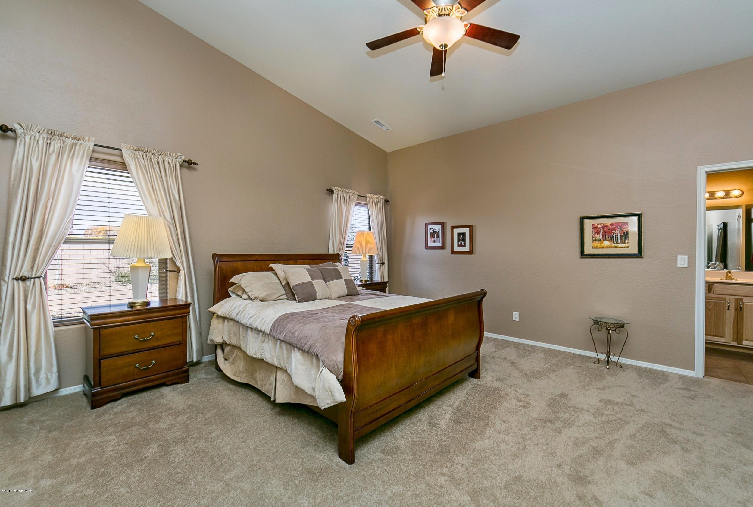4728 Edgemont Road Prescott Valley, AZ 86314 - Photo 8 of 17 a spacious bedroom with a bed and a chandelier