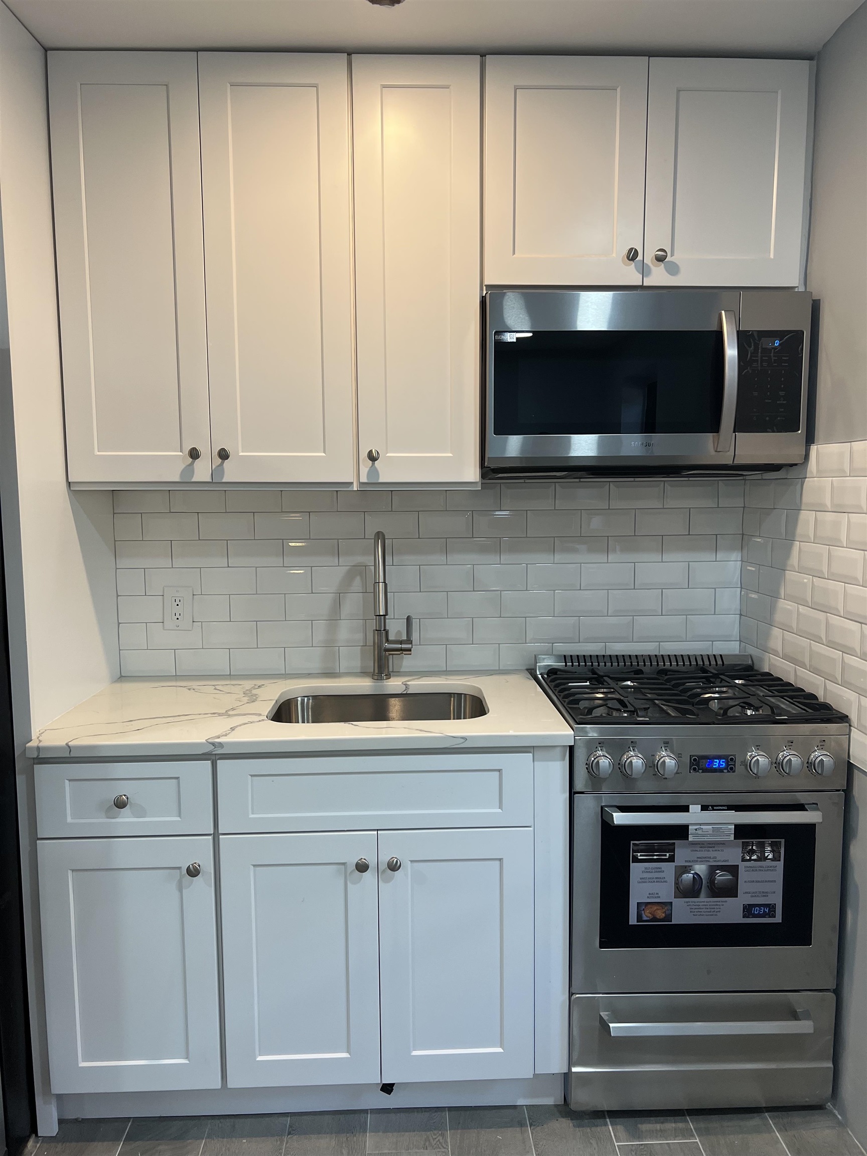 165 Vroom Street, Unit 1F Jersey City, NJ 07306 - Photo 7 of 11 a kitchen with granite countertop white cabinets and stainless steel appliances