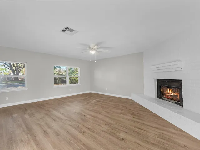 an empty room with windows and fireplace
