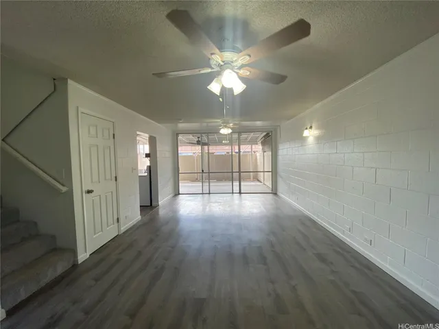 an empty room with wooden floor fan and windows