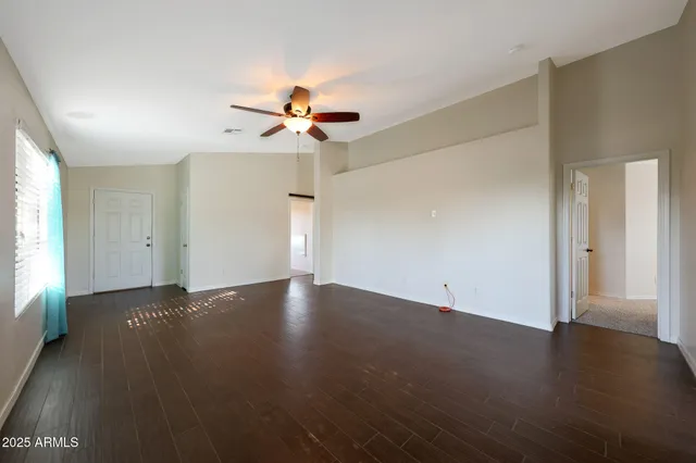 an empty room with windows and fan