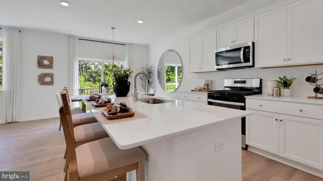 a kitchen with stainless steel appliances a white table chairs and a refrigerator