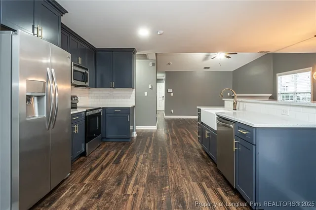 a kitchen with stainless steel appliances a sink dishwasher a refrigerator and cabinets