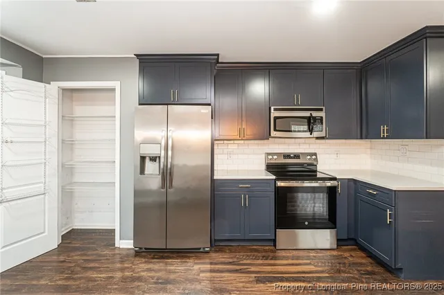a kitchen with granite countertop a refrigerator and a stove top oven