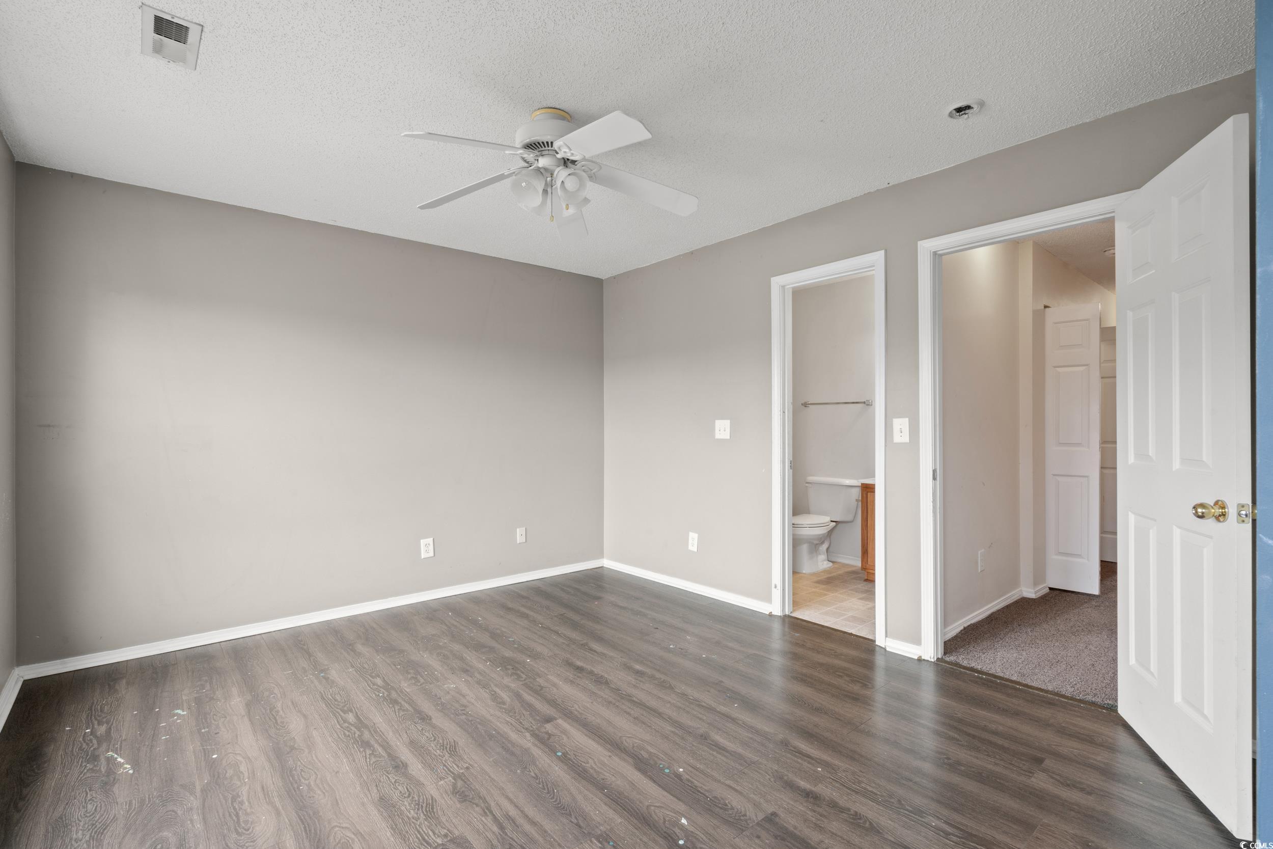 322 Kiskadee Loop, Unit 12E Conway, SC 29526 - Photo 16 of 36 Unfurnished bedroom featuring a textured ceiling, dark wood-type flooring, ceiling fan, and ensuite bath