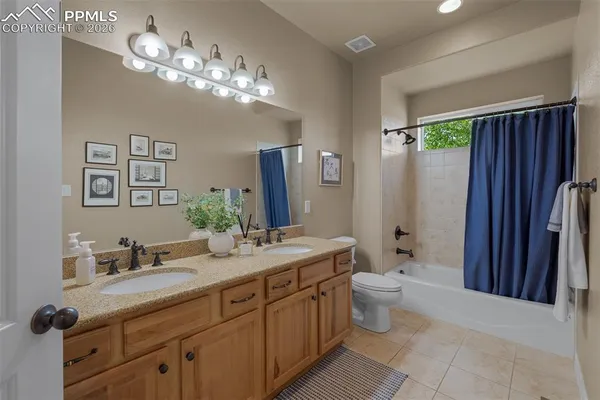 a spacious bathroom with a granite countertop sink a toilet a mirror a vanity and shower