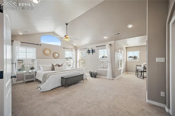 a large bedroom with a bed and ceiling fan