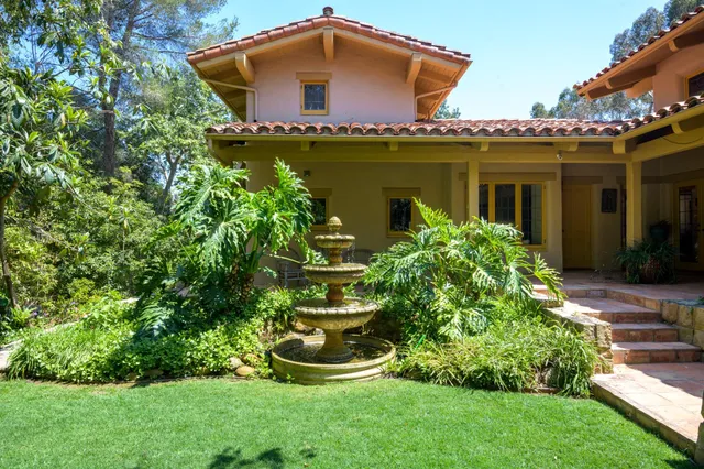 a front view of a house with a yard and potted plants