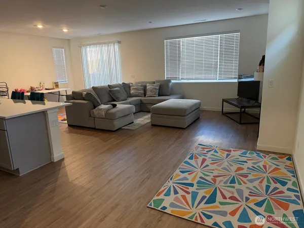 a living room with furniture a large window and wooden floor