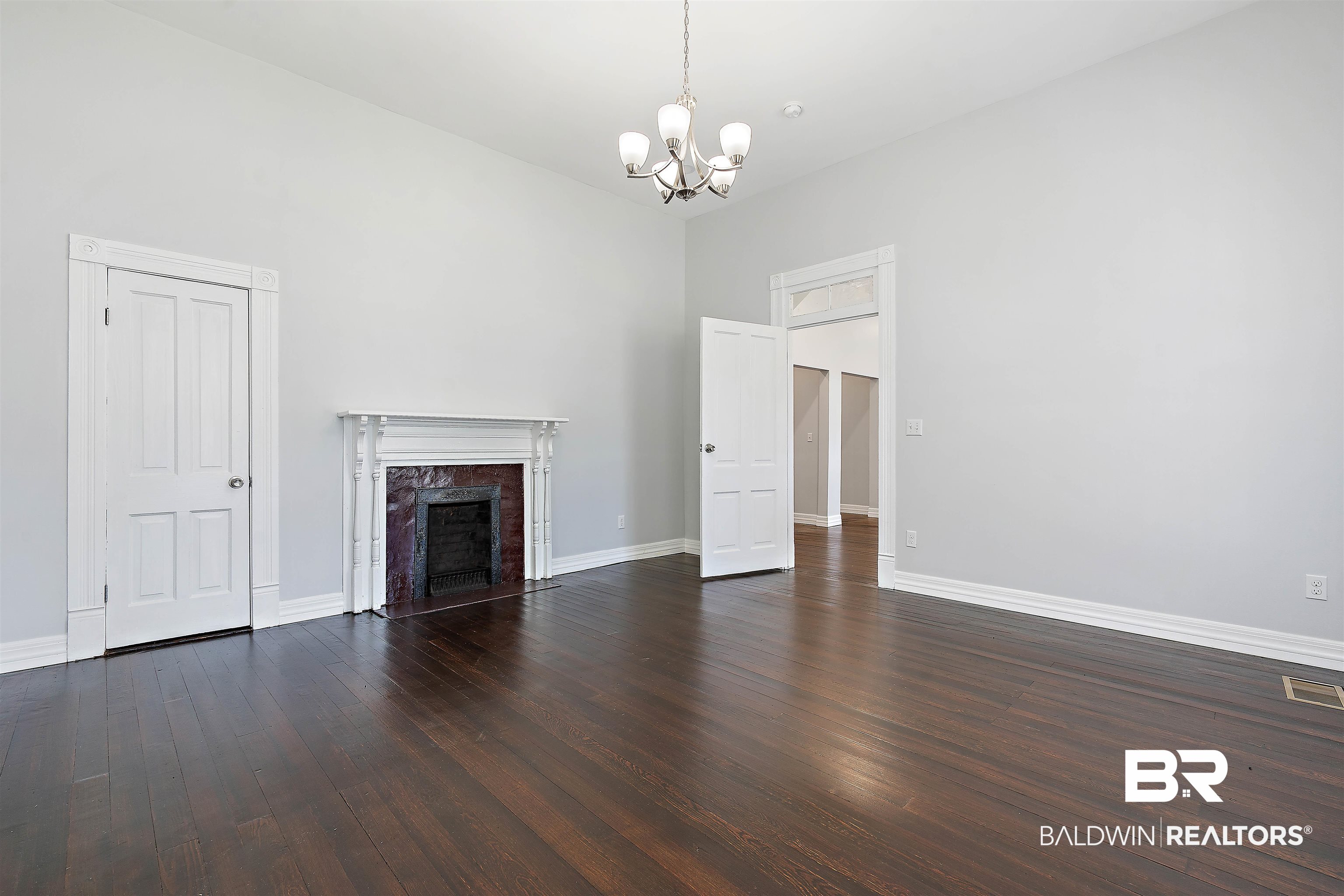 407 East 2nd Street Bay Minette, AL 36507 - Photo 19 of 40 Unfurnished living room featuring dark wood-type flooring, a fireplace, and a chandelier
