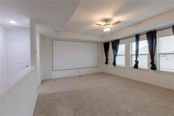 an empty room with chandelier fan and windows