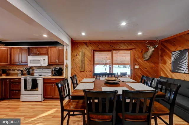 a dining hall with stainless steel appliances granite countertop a stove a refrigerator a dining table and chairs with wooden floor