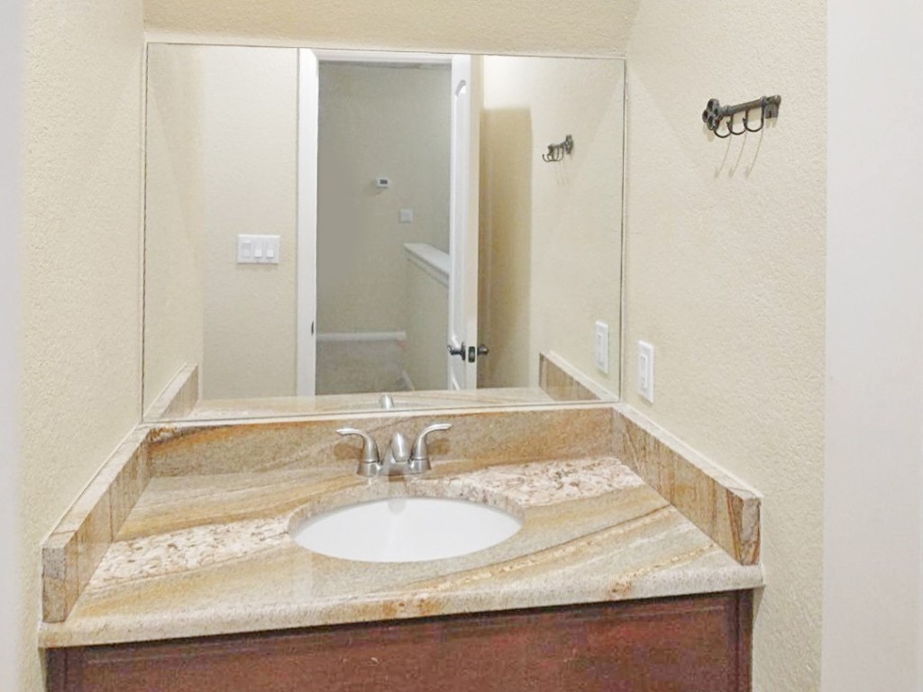 16219 Oxbow Trail, Unit UPSTAIRS Buda, TX 78610 - Photo 6 of 7 a bathroom with a granite countertop sink and a mirror