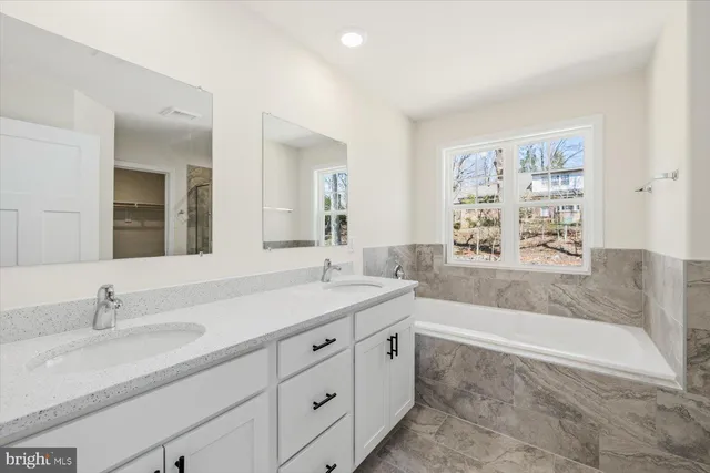 a bathroom with a granite countertop sink mirror bathtub and toilet