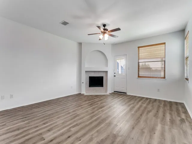 a view of empty room with wooden floor and ceiling fan