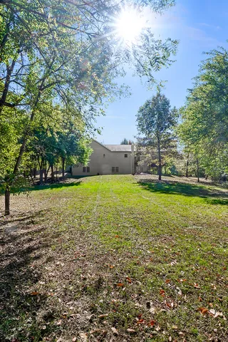 a view of house with backyard and trees
