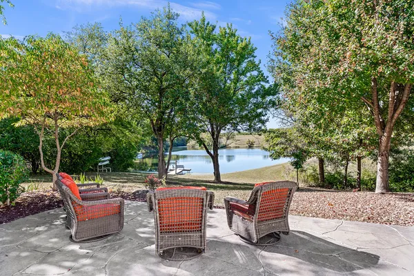 a view of a patio with table and chairs floor to ceiling window and trees