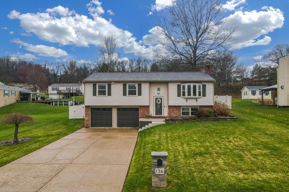 a view of house with a big yard and large trees