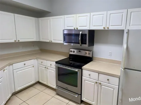 a kitchen with white cabinets and appliances