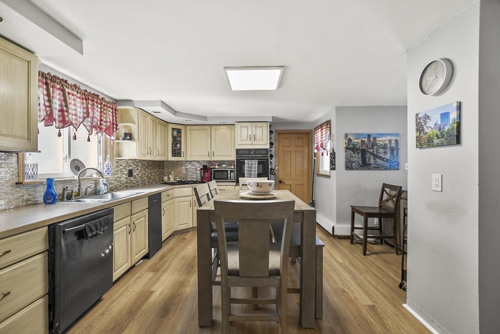 82 Cedar Street Everett, MA 02149 - Photo 28 of 41 a kitchen with stainless steel appliances granite countertop a refrigerator a sink dishwasher a dining table and chairs with wooden floor