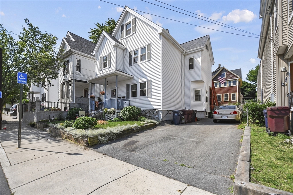 82 Cedar Street Everett, MA 02149 - Photo 3 of 41 a view of a white house with large windows and a small yard