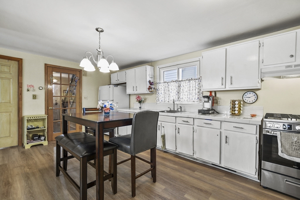82 Cedar Street Everett, MA 02149 - Photo 5 of 41 a kitchen that has a lot of cabinets in it with stainless steel appliances granite countertop a stove a sink dishwasher and white cabinets with wooden floor