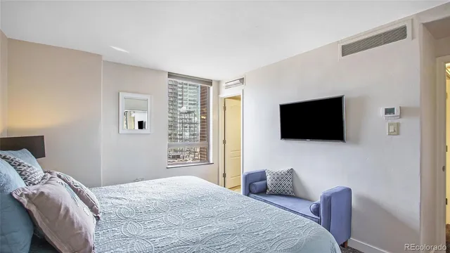 a bedroom with a bed a television and a window