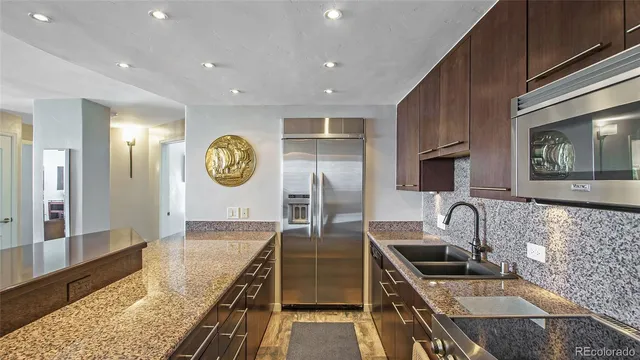 a kitchen with stainless steel appliances granite countertop a sink a stove and a refrigerator