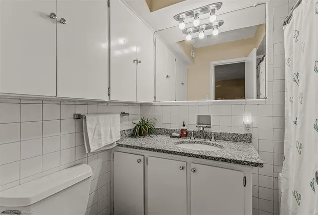 a bathroom with a granite countertop sink a toilet and mirror