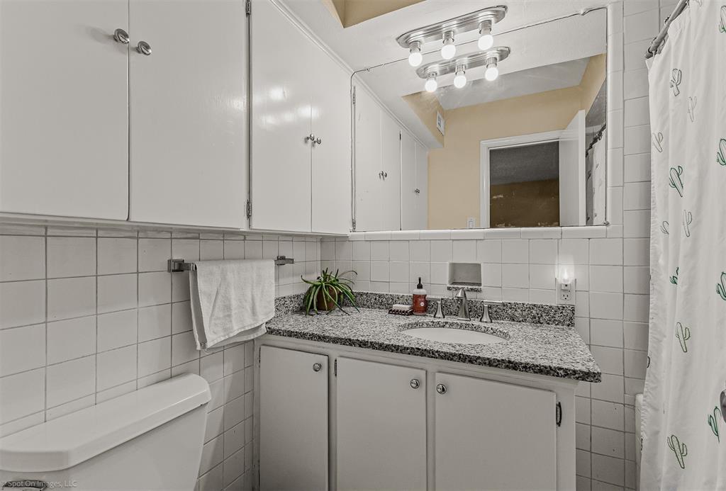 7910 Northaven Road, Unit B Dallas, TX 75230 - Photo 11 of 27 a bathroom with a granite countertop sink a toilet and mirror
