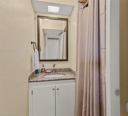a bathroom with a granite countertop sink and a mirror