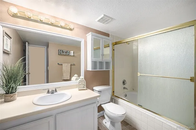 a bathroom with a granite countertop sink toilet a mirror a vanity and shower