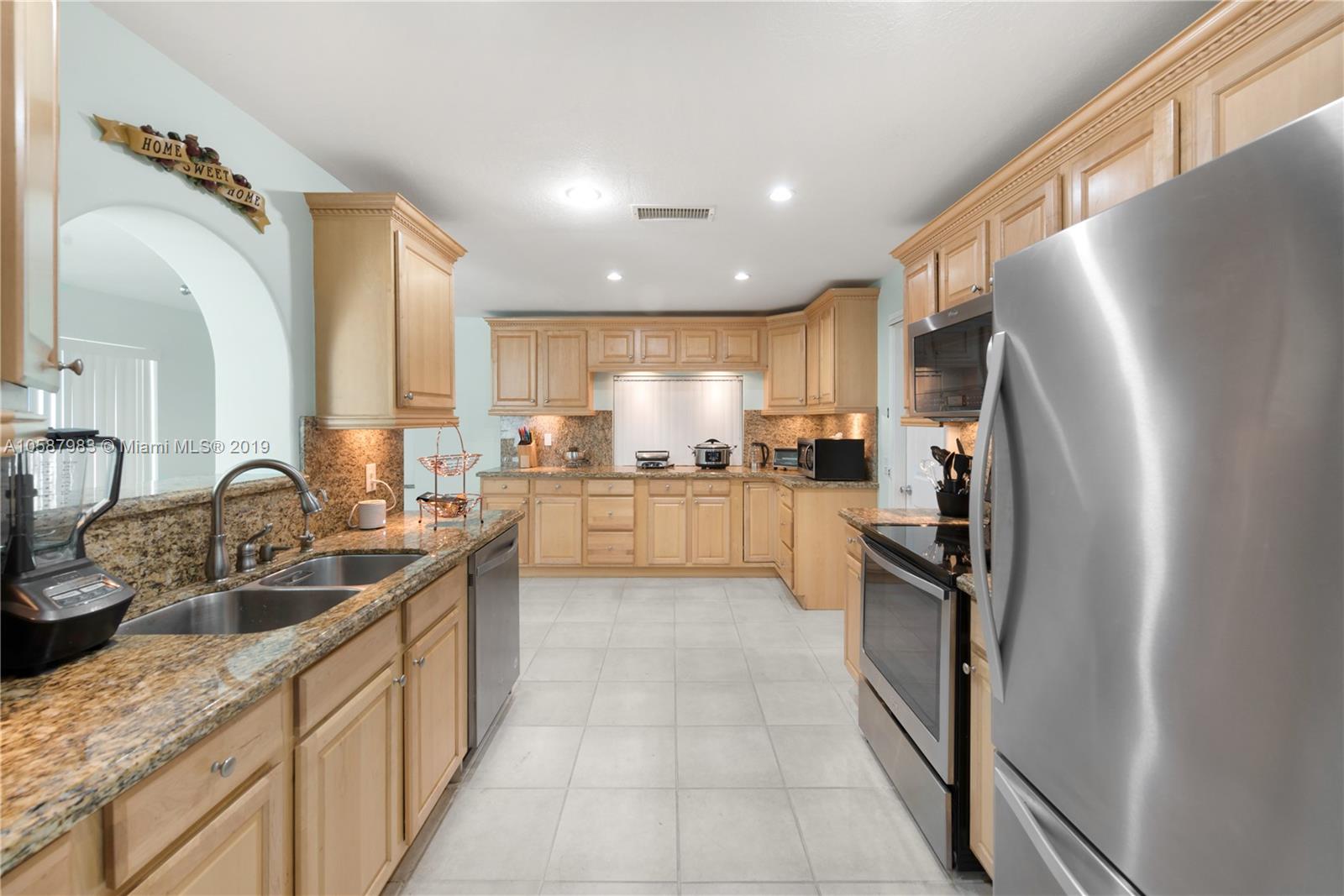 8912 Southwest 6th Street Boca Raton, FL 33433 - Photo 3 of 19 a kitchen with stainless steel appliances granite countertop a refrigerator sink and wooden cabinets