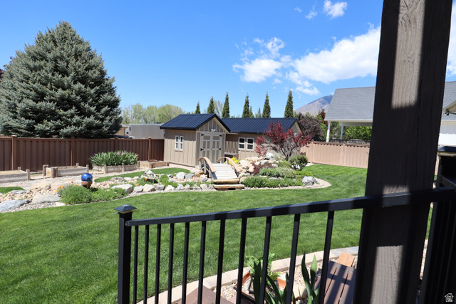 1055 North 1000 East Mapleton, UT 84664 - Photo 73 of 112 Expansive backyard featuring a green lawn, wood fence, and a storage shed with a dark metal roof