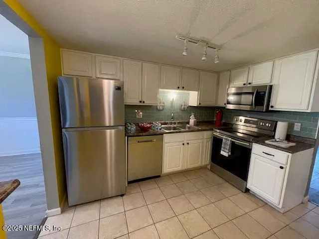 a kitchen with granite countertop a refrigerator sink and cabinets