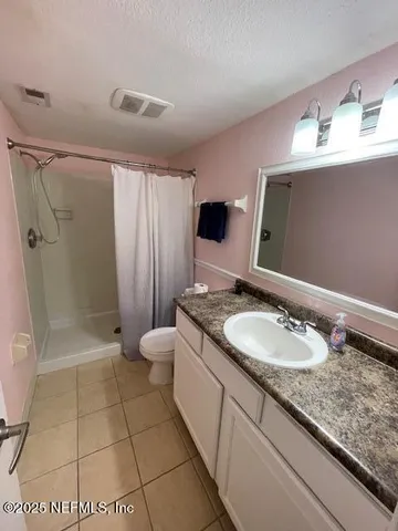 a bathroom with a granite countertop sink a toilet and shower