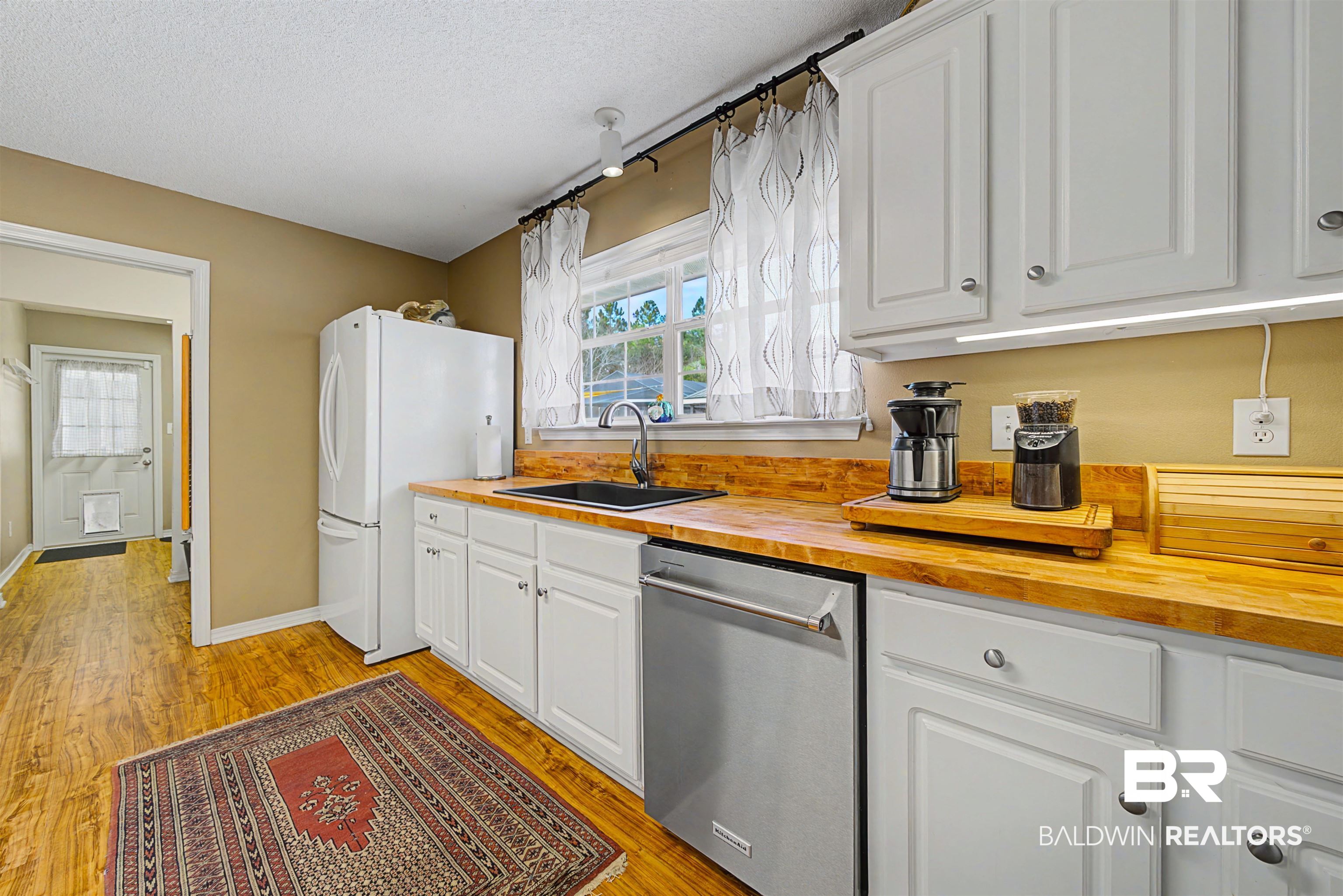 313 Collinwood Loop Foley, AL 36535 - Photo 13 of 36 Kitchen with white cabinetry, butcher block countertops, granite on island, stainless dishwasher, stainless range and hood.