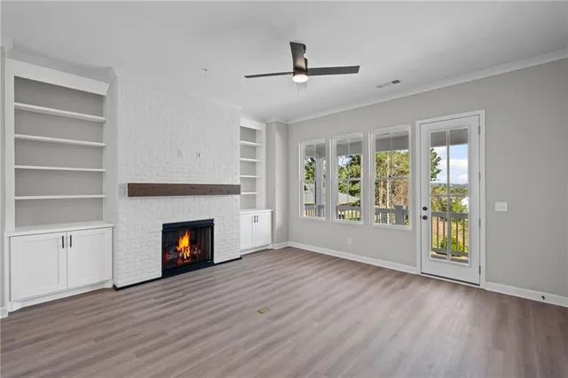 a view of an empty room with wooden floor fireplace and a window