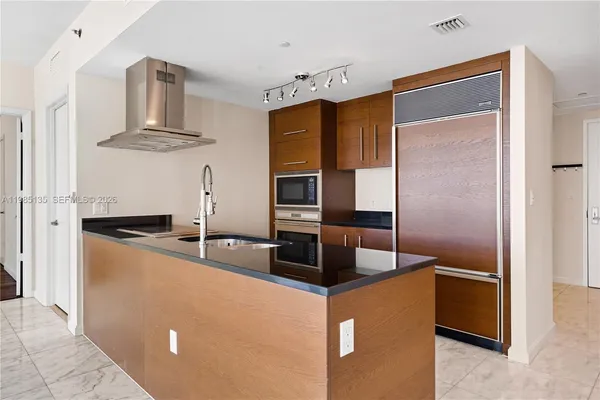 a kitchen with stainless steel appliances granite countertop a refrigerator a stove and a sink with wooden floor