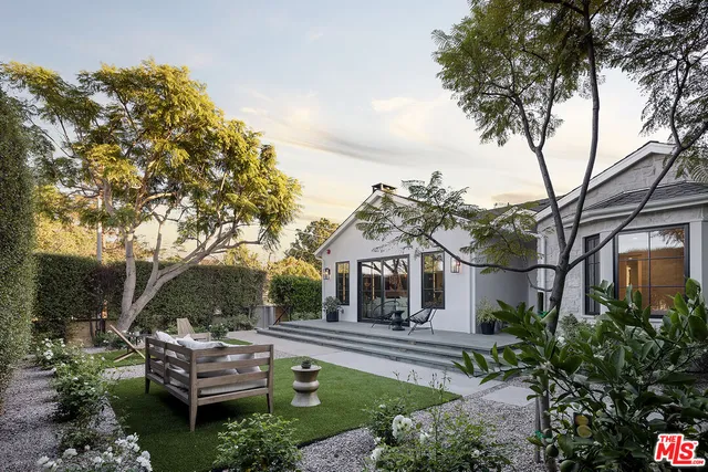 a front view of a house with garden and trees