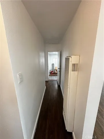 a view of a hallway with wooden floor and a bathroom